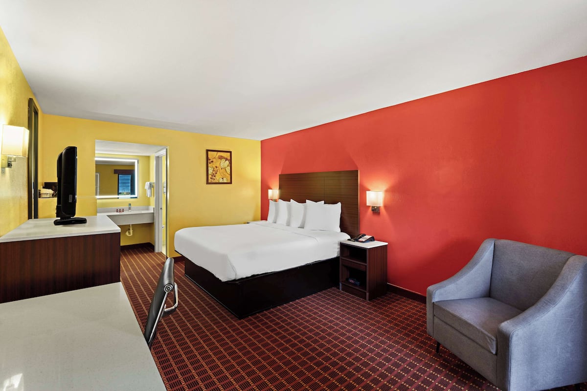 A hotel room with a bed, a desk, a chair, and a nightstand.