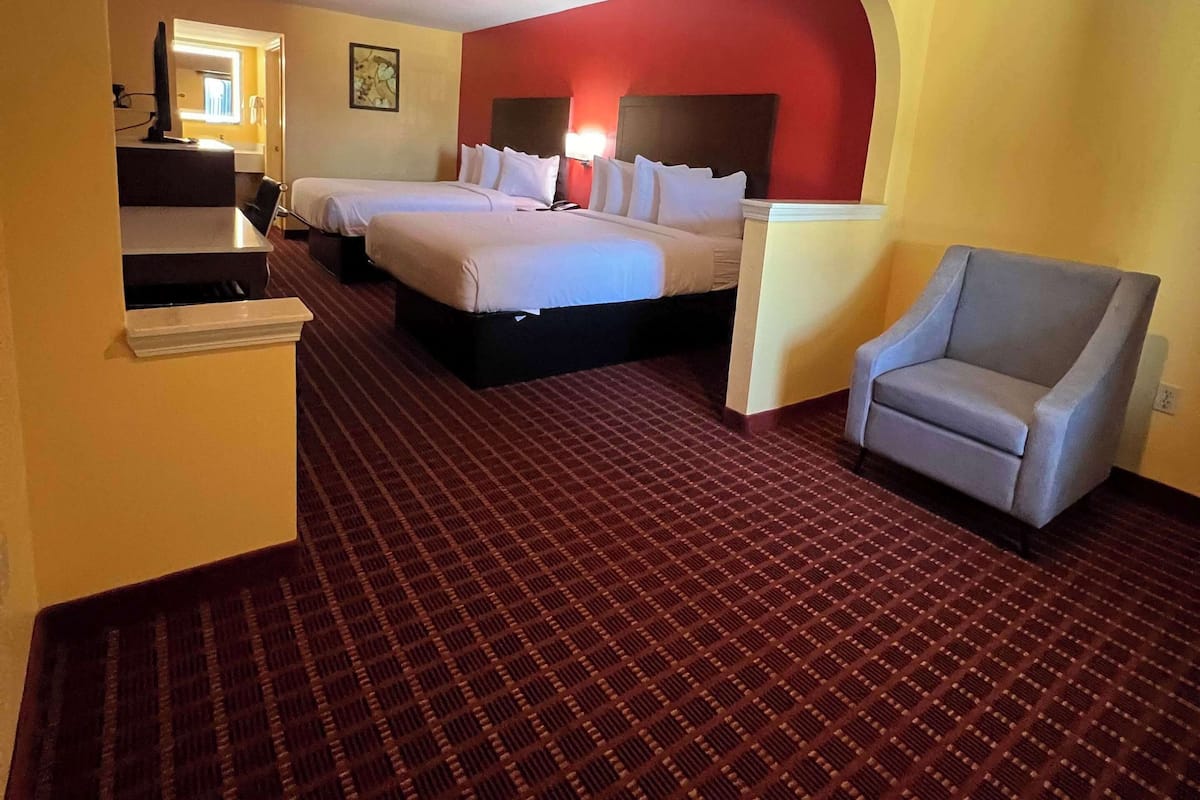 A hotel room with two beds, a desk, and a chair.