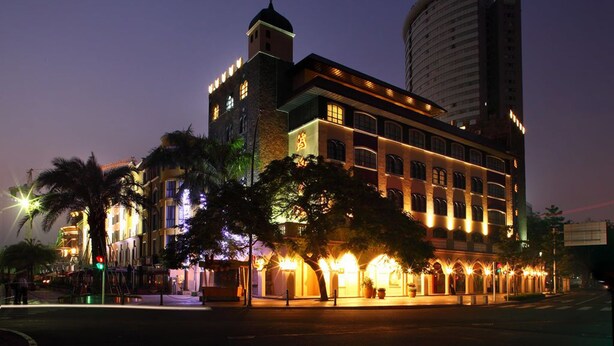 A hotel with a prominent tower, large windows, and a well-lit facade at dusk. - Honlux Apartment (Shenzhen)