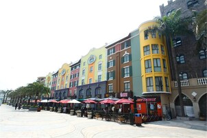 A row of colorful buildings with outdoor seating areas and palm trees.