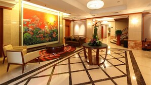 A lobby with a large floral mural, a round coffee table, seating area, and a staircase. - Honlux Apartment (Shenzhen)