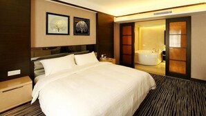 A modern hotel room with a large bed, a nightstand, a wall-mounted TV, and a sliding door leading to a bathroom with a bathtub. - Honlux Apartment (Shenzhen)
