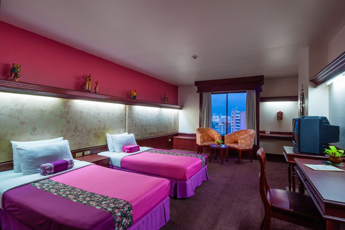 Una habitación de hotel con dos camas, un escritorio, una silla y un televisor.