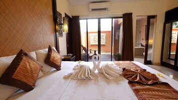 Habitación de hotel con una cama grande, dos almohadas, un muro decorativo, una ventana con cortinas y vistas al exterior.