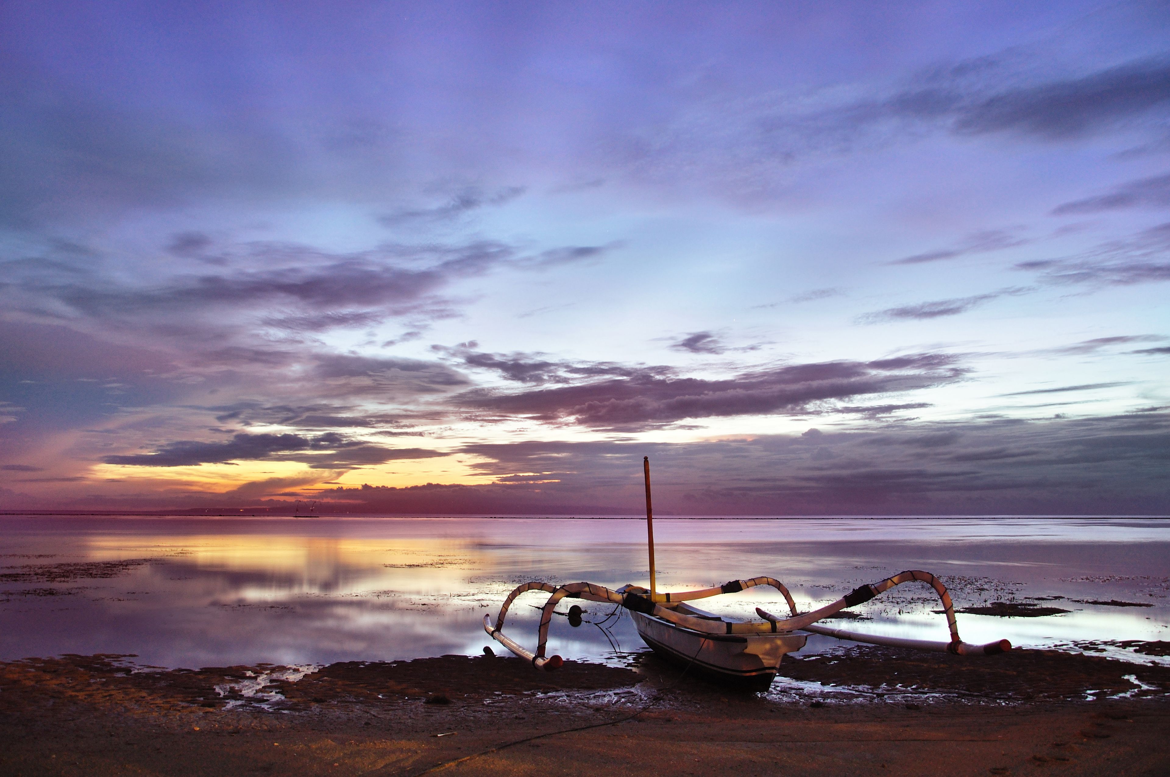 A boat on a calm body of water with a sunset in the background.