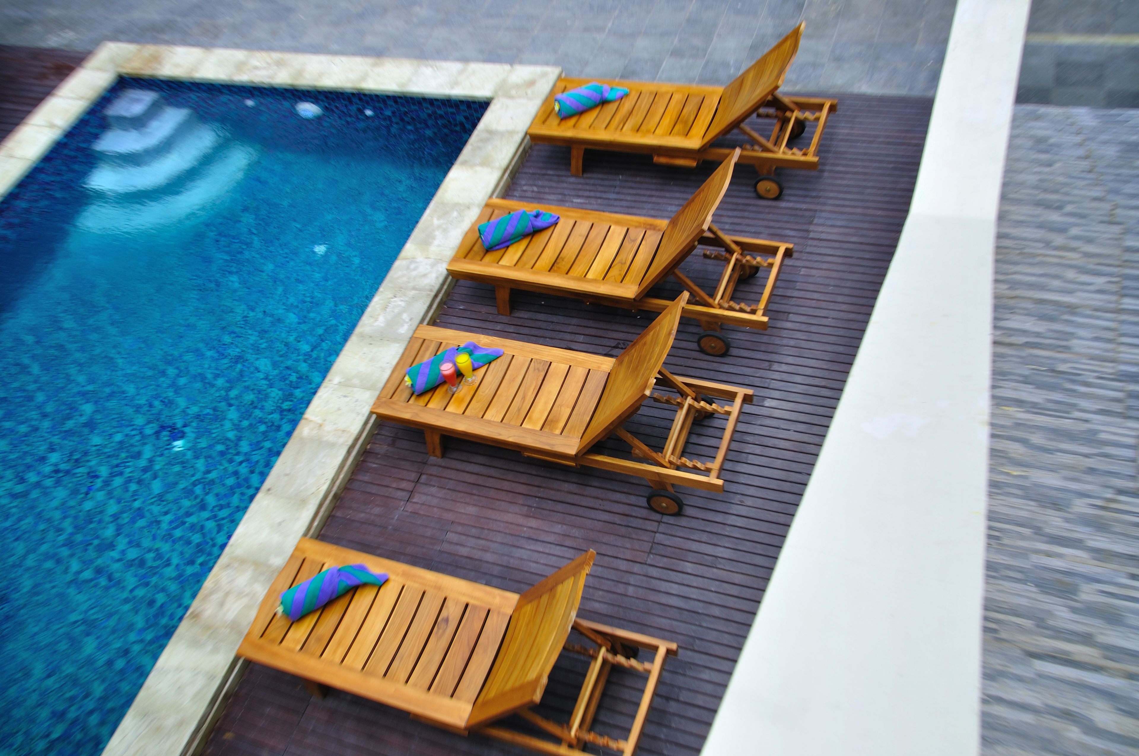 A poolside area with wooden lounge chairs and a small pool.