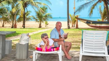 Relax on the beach with a clear ocean view, lounge chairs, and a nearby table.