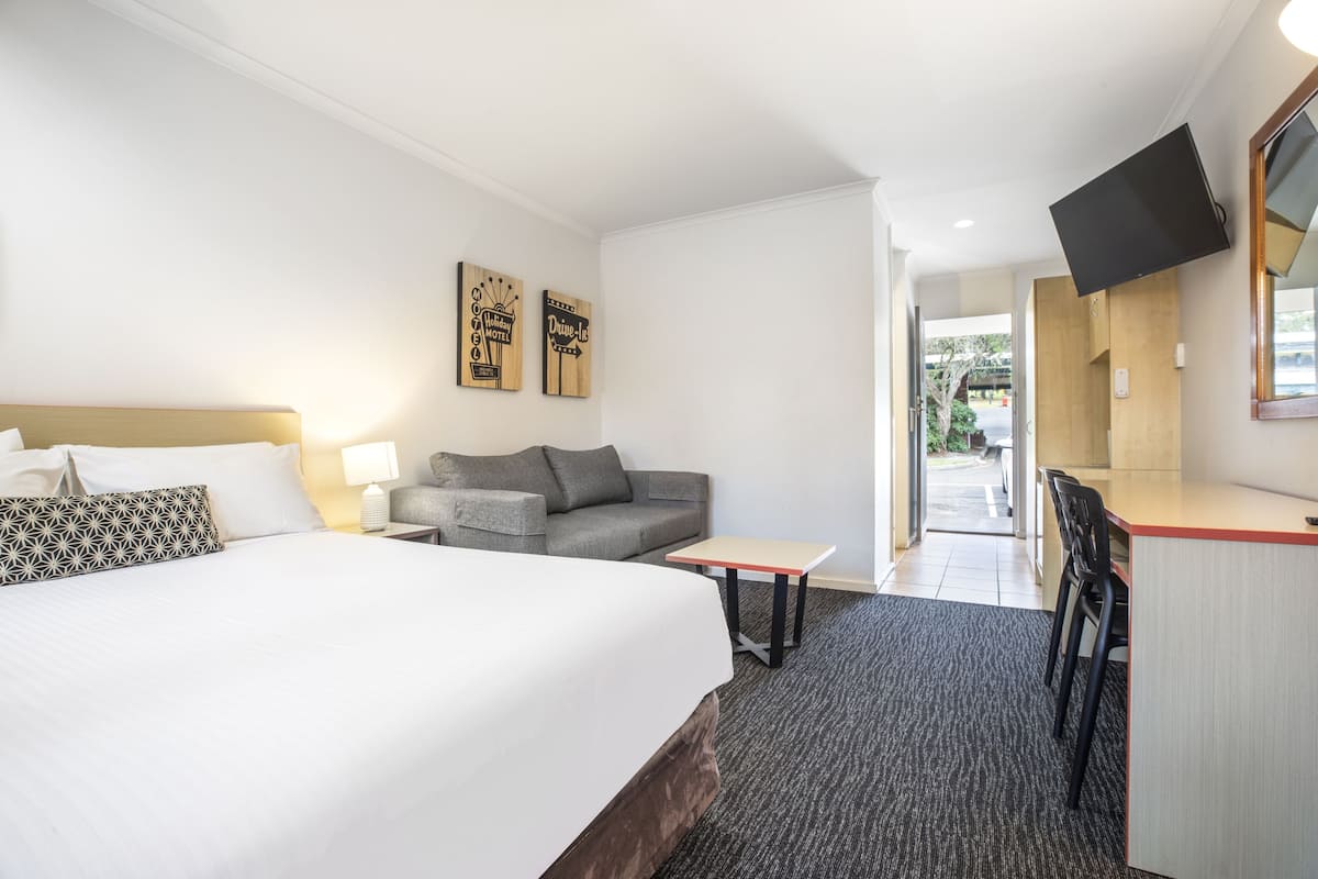 Une chambre d’hôtel équipée d’un lit, d’un canapé, d’un bureau et d’un téléviseur fixé au mur.
