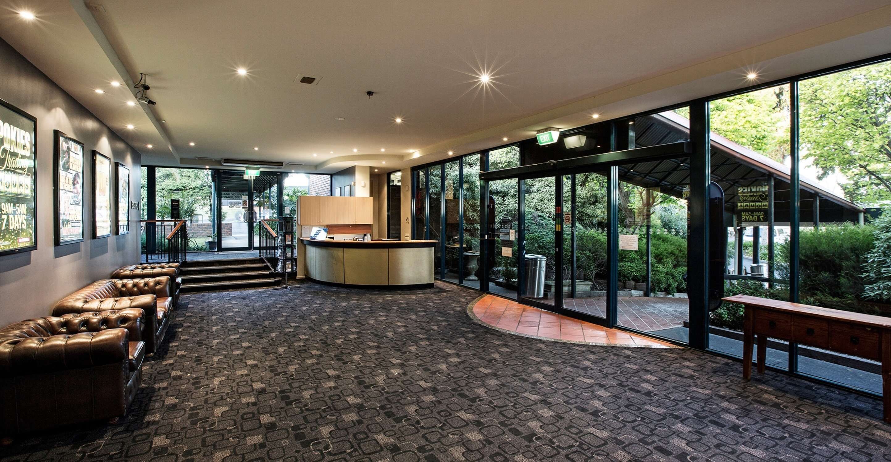 A spacious lobby with a reception desk, seating area, and large windows offering a view of the outdoors.