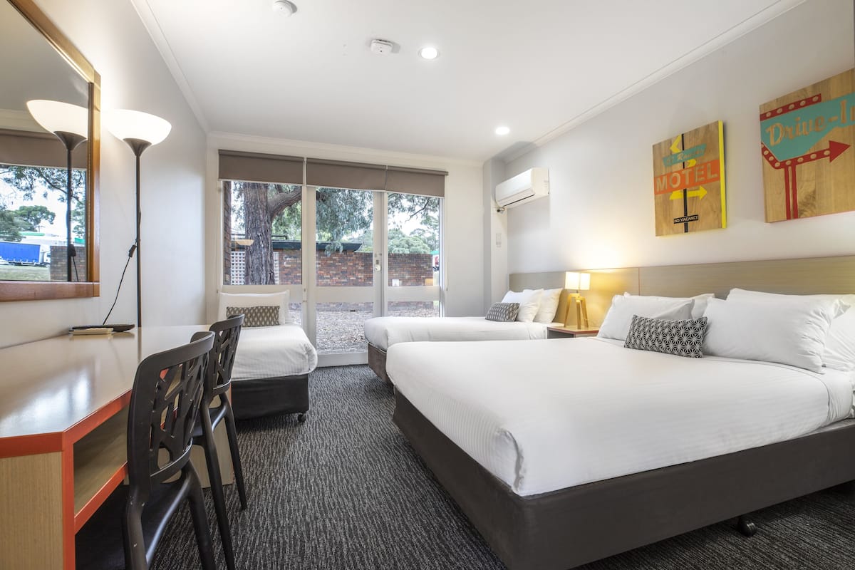 Une chambre d’hôtel avec deux lits, un bureau, des chaises et une grande fenêtre.