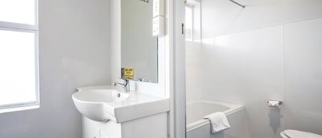 A modern bathroom with a white sink, mirror, and bathtub.