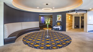 Un espacio de estar circular con piso estampado, una mesa central e iluminación empotrada en el techo.