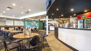 Vestíbulo de hotel con recepción, mesas y sillas para comer.