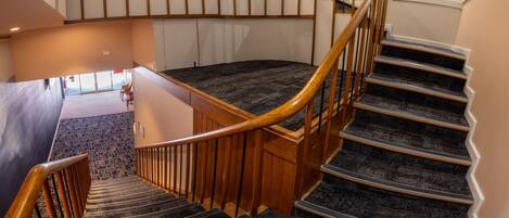 Una escalera de caracol con barandillas de madera y peldaños alfombrados que conducen a una plataforma.