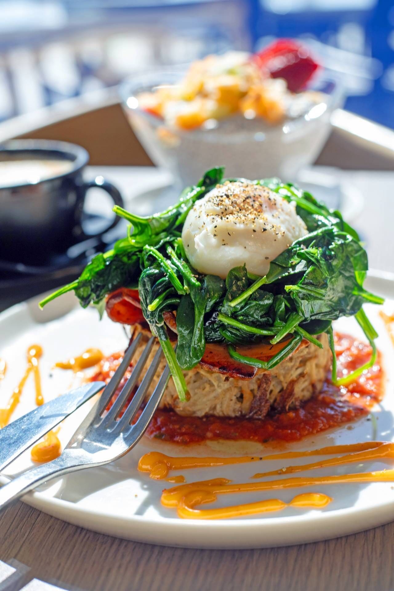 A plate of food with a poached egg, spinach, and a tomato-based sauce.