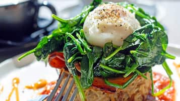 A plate of food with a poached egg, spinach, and a tomato-based sauce.
