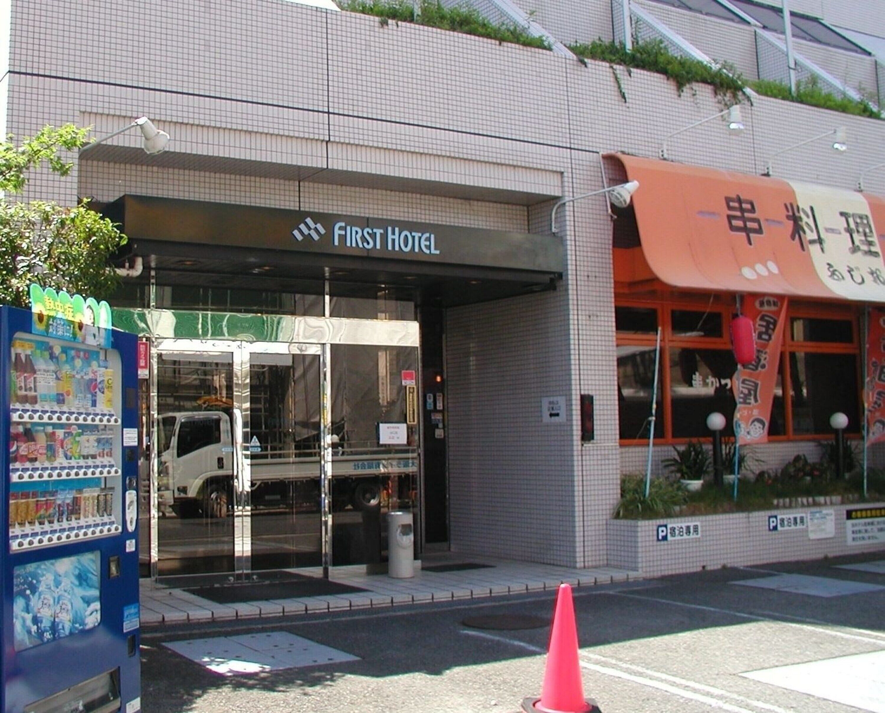 A hotel entrance with a glass door, a vending machine, and a parking sign.