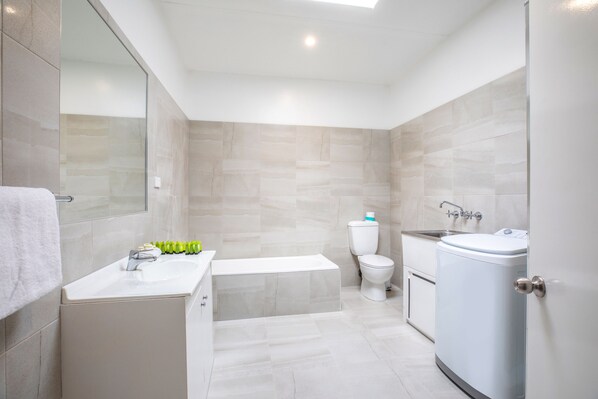 A modern bathroom with a bathtub, toilet, and sink.