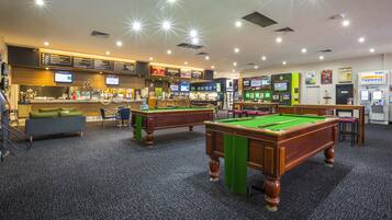 A pool hall with multiple pool tables, a bar area, and a menu board.