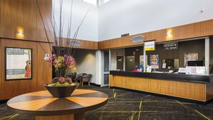 A hotel reception area with a reception desk, a bulletin board with a guitar poster, and a decorative vase with flowers. - Nightcap at Coolaroo Hotel (Coolaroo)