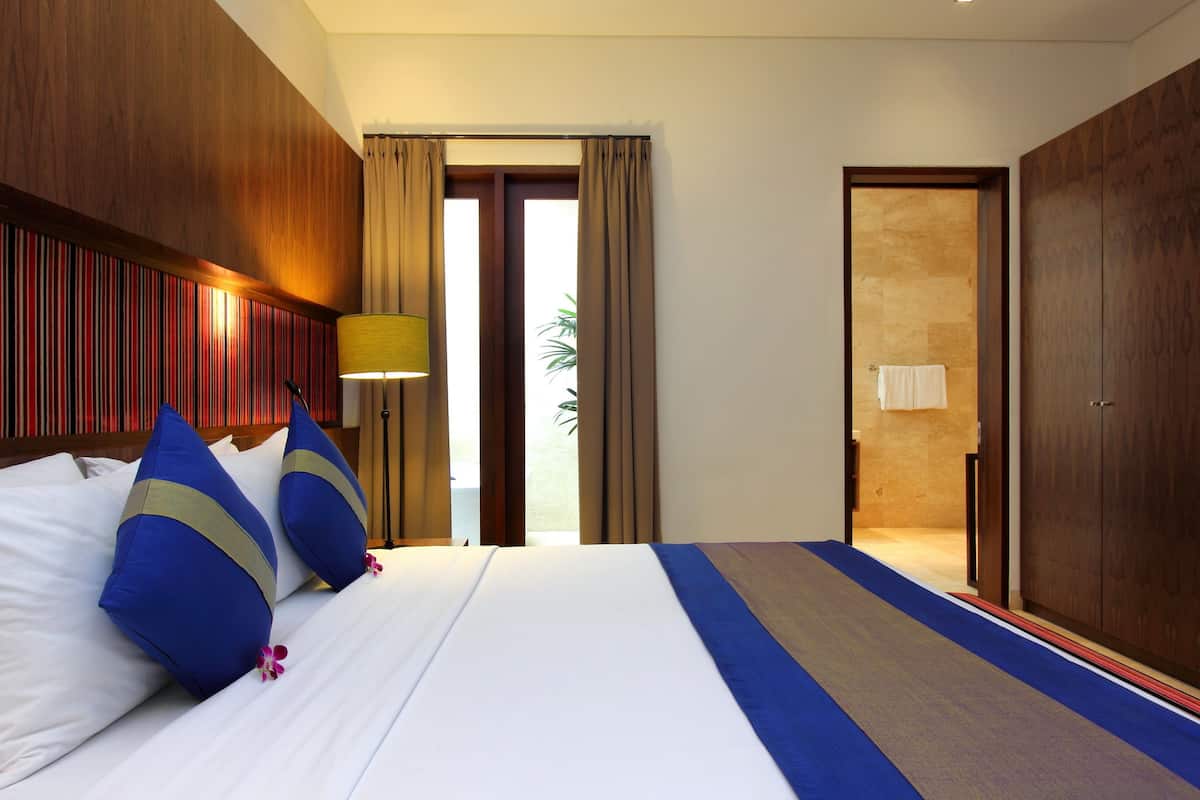A hotel room with a large bed, wooden headboard, and a view of the outdoors.