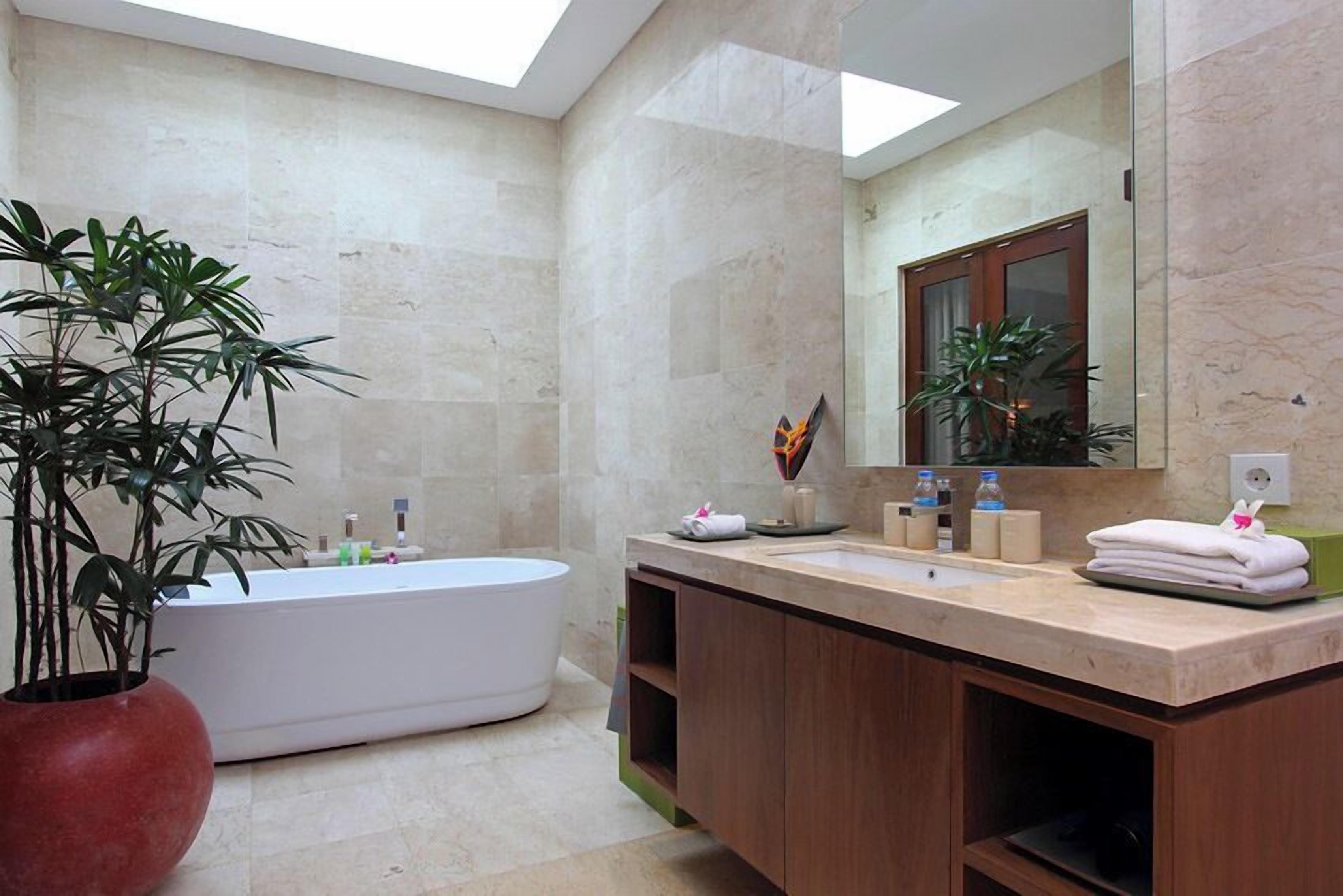 A modern bathroom with a freestanding bathtub, a large mirror, and a vanity with a sink and countertop.