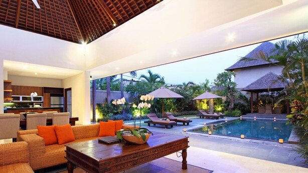 Espaço moderno em ambientes internos com piscina, cadeiras de descanso e área de refeições.