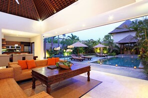 Un espacio interior moderno con piscina, sillones de descanso y zona de comedor.