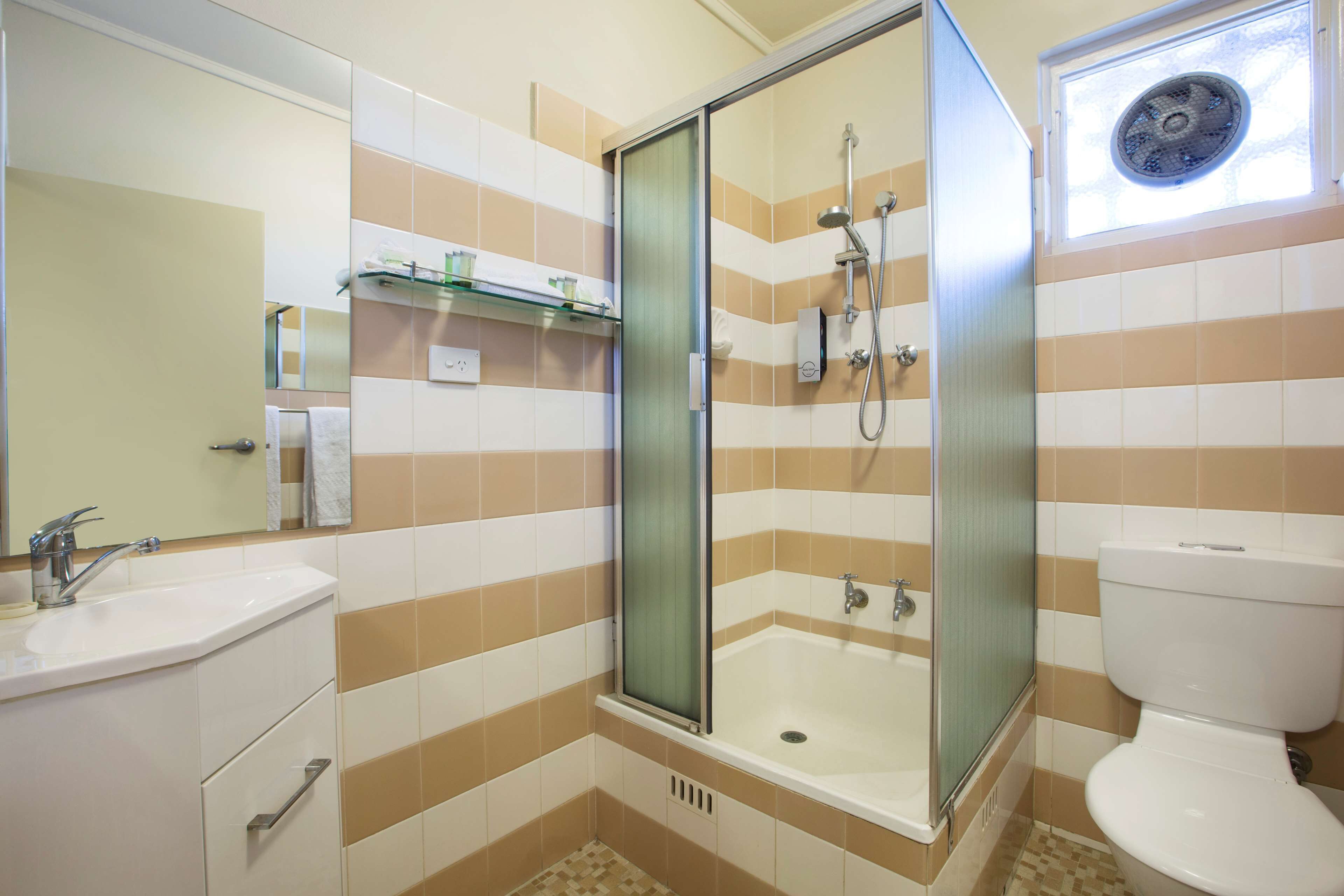 Une salle de bain avec une douche à parois de verre, un lavabo et des toilettes.