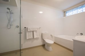 Ein modernes Badezimmer mit Toilette, Badewanne und Dusche.