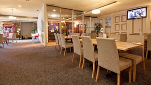 Eine Hotellobby mit einer Sitzecke, einem Fernsehbildschirm und einem Spielbereich für Kinder im Hintergrund.