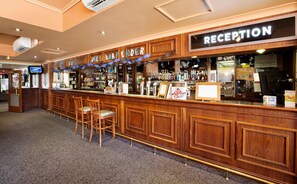 Eine Bar mit Empfangstresen, Holzbalken und Barhocker.
