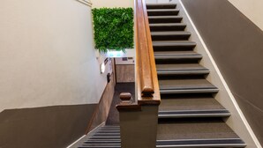 Eine Treppe mit Holzgeländer, Teppichstufen und einer an der Wand befestigten Zimmerpflanze.