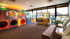 A brightly lit indoor play area with colorful play structures and a claw machine. - Nightcap at Excelsior Hotel (Thomastown)