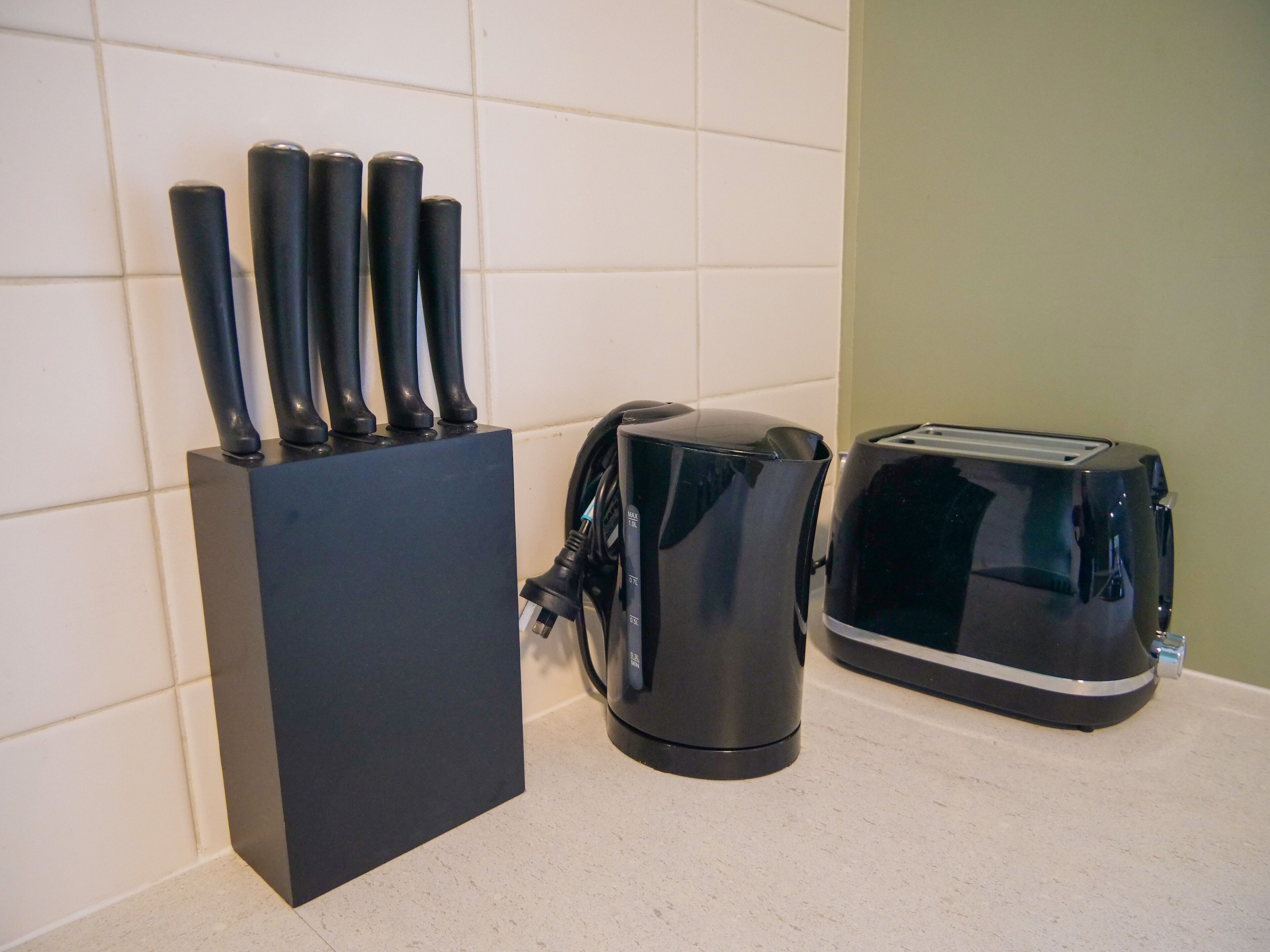 A kitchen with a black appliance, a toaster, and a coffee maker on the counter.