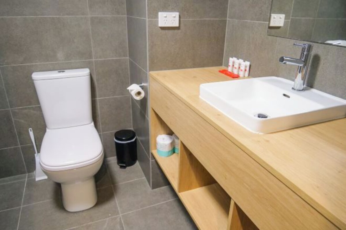 A modern bathroom with a toilet, sink, and a mirror.
