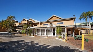 Un hotel con entrada cubierta, palmeras y un letrero que dice Oasis Can Bar.