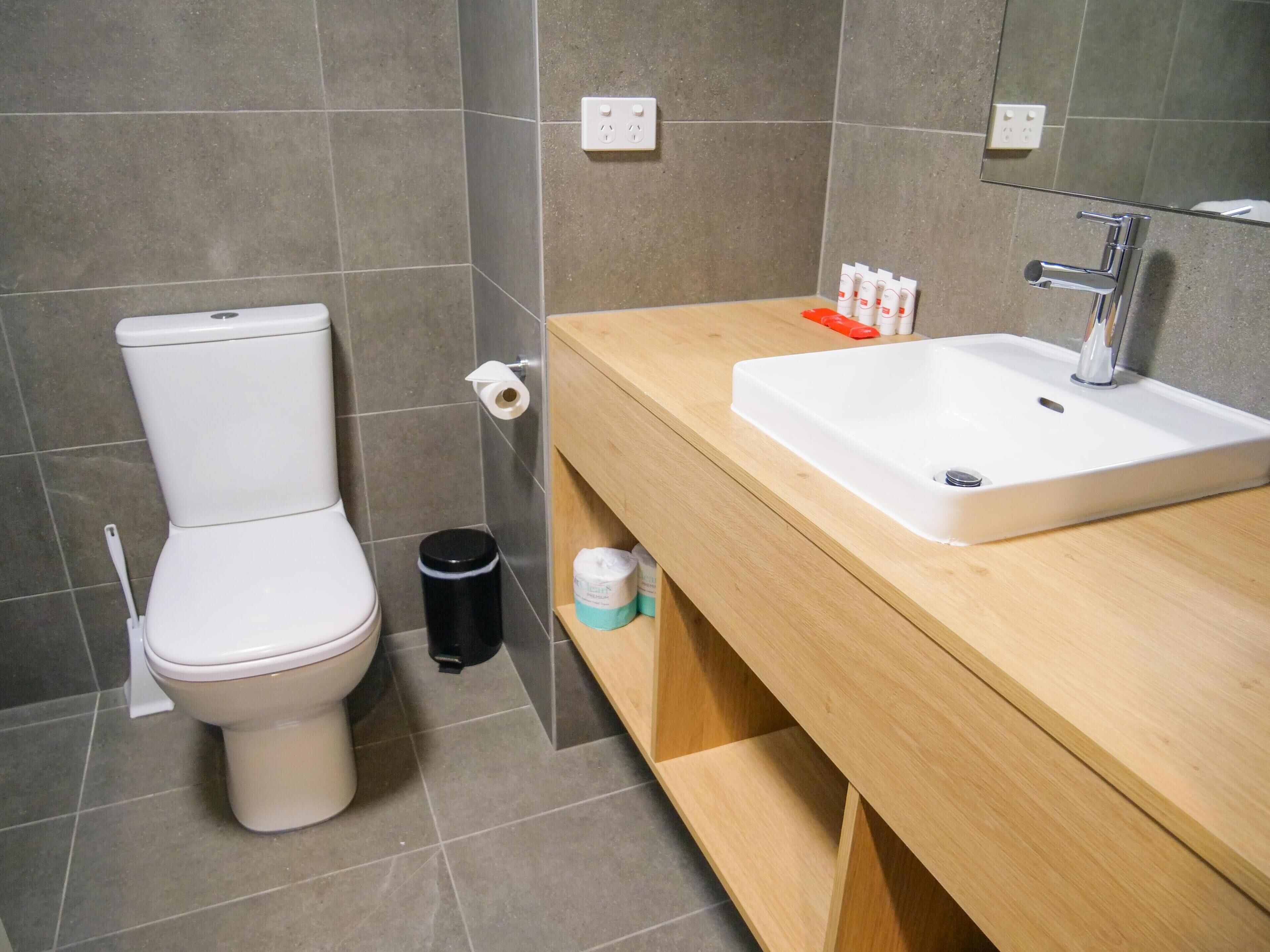Un bagno moderno con toilette, lavabo e specchio.