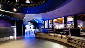 Eine großzügige Lobby mit gewölbter Decke, einer zentralen Treppe und einer Bar.