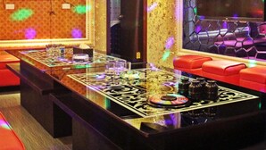 Een kamer met een grote flatscreen televisie, een salontafel met een CD en rode zitplaatsen.