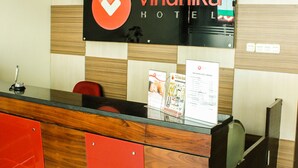 Una recepción con un panel de madera, tres relojes y un letrero para Vindhika Hotel.