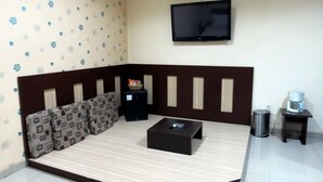 Una habitación con sofá, una mesa de centro, televisor montado en la pared y una mesita con cafetera.