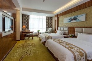 A hotel room with two beds, a desk with a lamp, a TV, and a large painting on the wall. - Oubon International Hotel (Guangzhou)