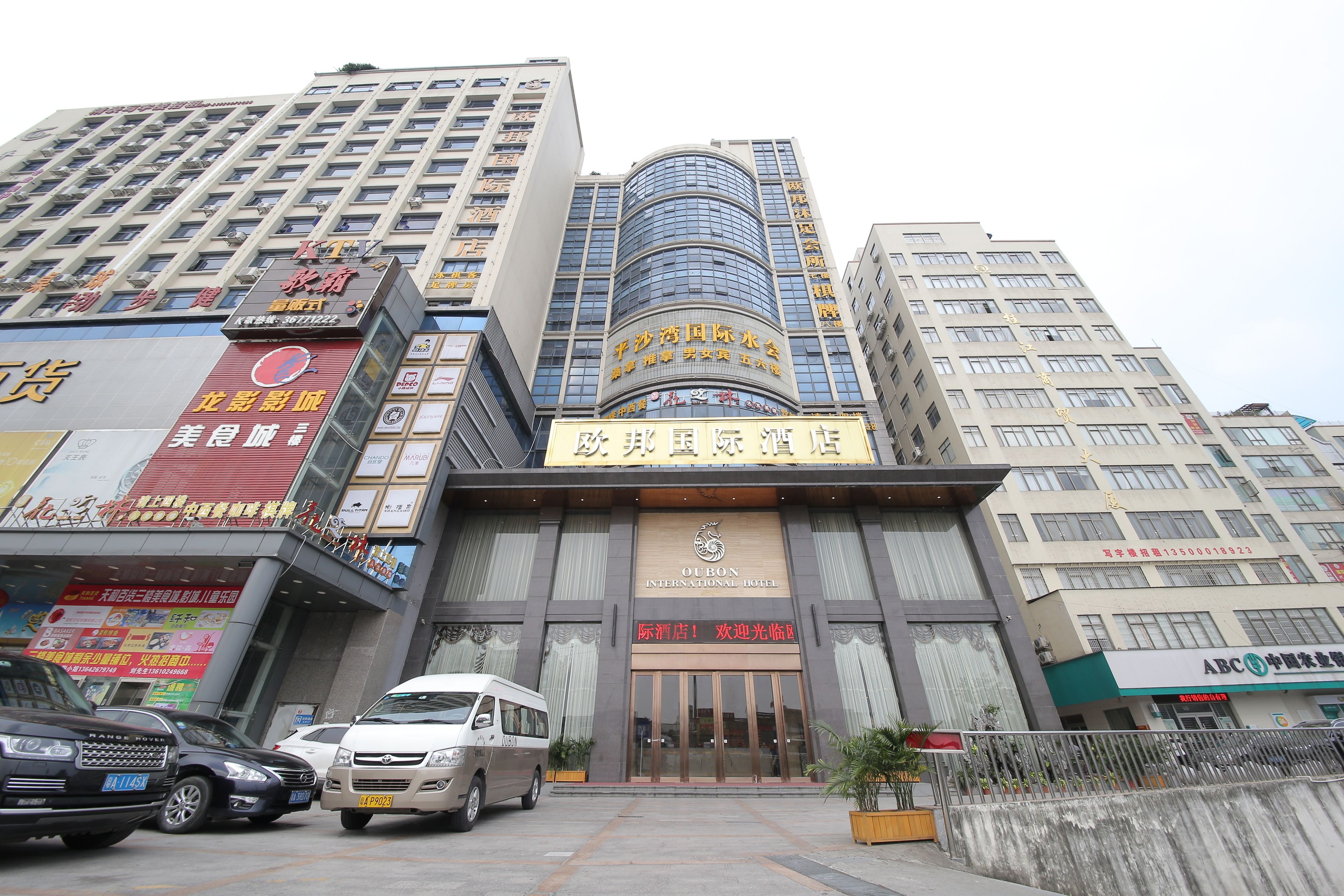 A hotel with a prominent sign, multiple floors, and a parking area with cars.