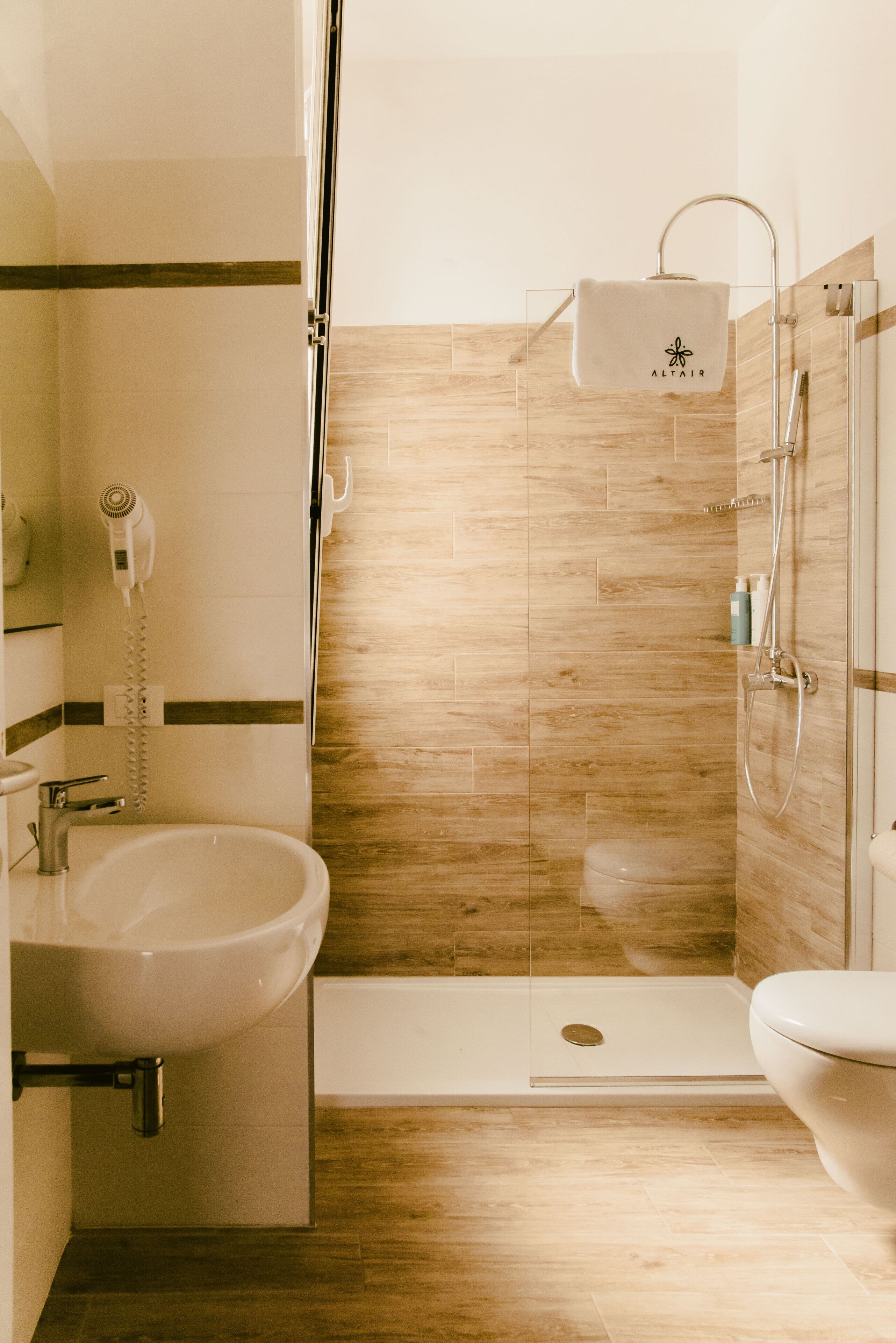 Un baño moderno con ducha envuelta en vidrio, lavamanos independiente y un inodoro.