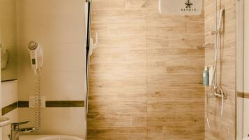 Un baño moderno con ducha envuelta en vidrio, lavamanos independiente y un inodoro.