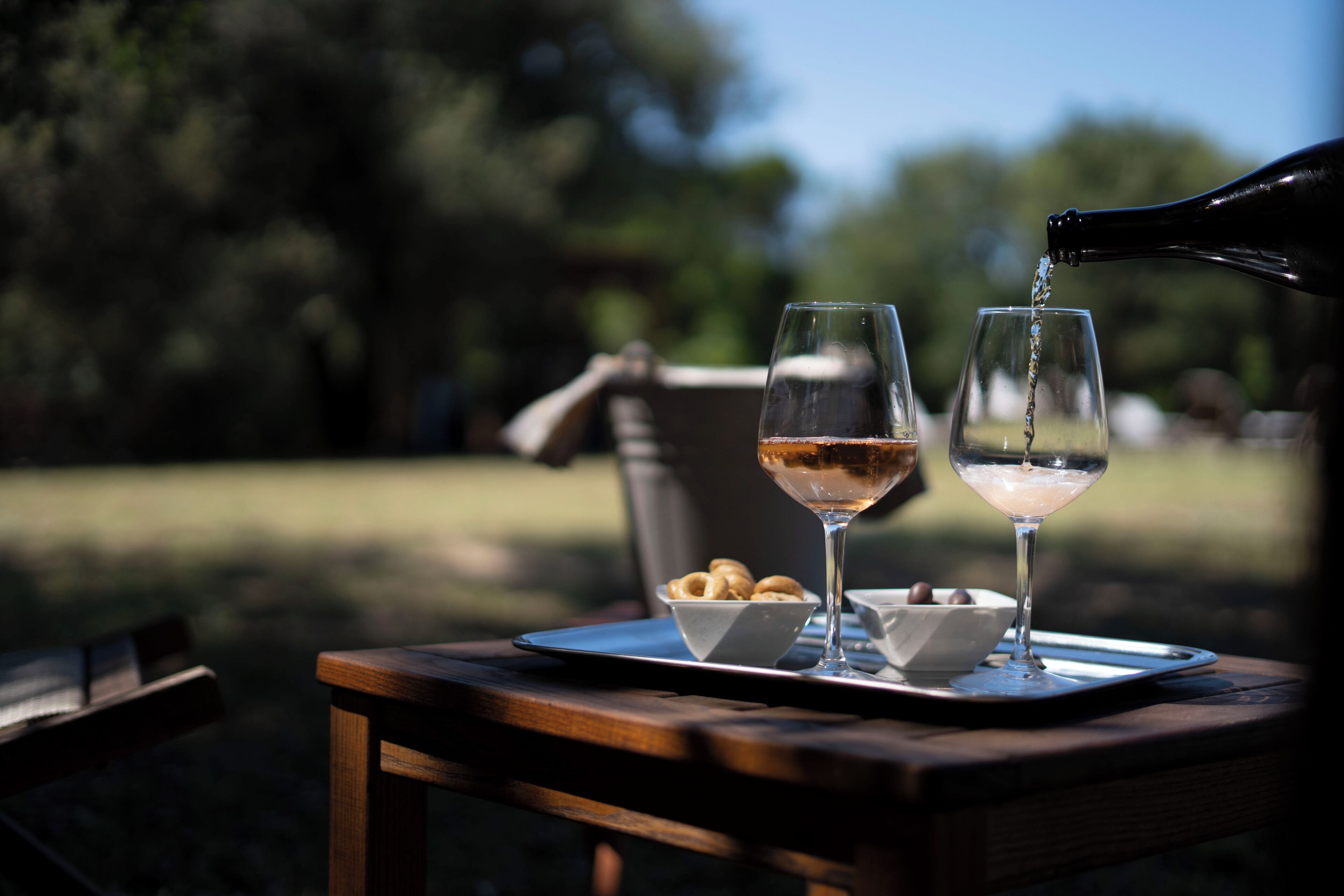 Two glasses on a tray with a bottle pouring into one.