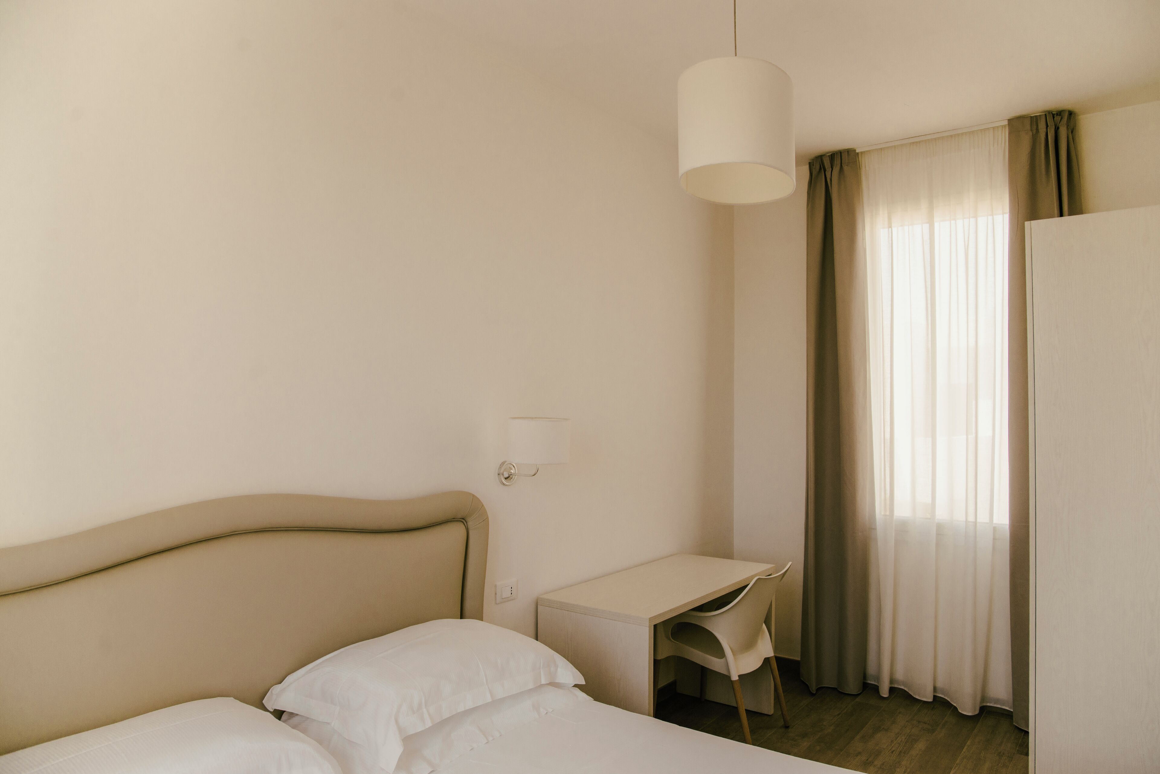 A hotel room with a bed, a desk, and a chair.