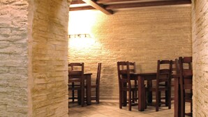 Un arco de piedra que da paso a un comedor con sillas de madera y suelo de baldosas.