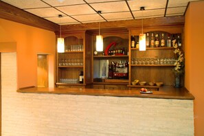 A bar area with wooden shelves, hanging lights, and a brick wall. - Hotel Hispania (Zaragoza)